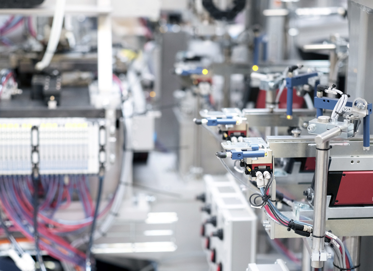 Nærbillede af industriel automatisering, der viser komplicerede maskiner, ledninger og robotkomponenter på en produktionslinje.